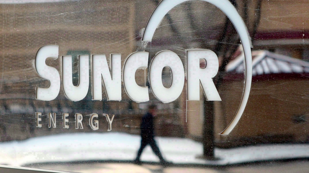 A pedestrian is reflected in a Suncor Energy sign in this photo taken in Calgary on Feb. 1, 2010. (Jeff McIntosh/THE CANADIAN PRESS)