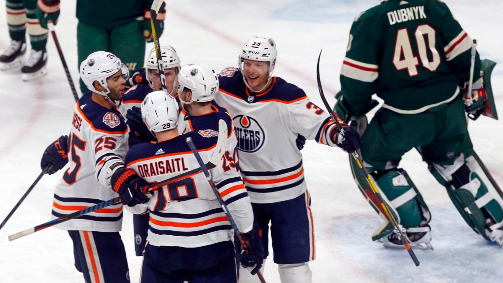 Edmonton Oilers' Leon Draisaitl, back to camera, of Germany, is congratulated by teammates after his power-play goal against Minnesota Wild goalie Devan Dubnyk, right, during the third period of an NHL hockey game Thursday, Feb. 7, 2019 in St. Paul, Minn. At left is Oilers' Darnell Nurse, who scored a first-period goal. (AP Photo/Jim Mone)