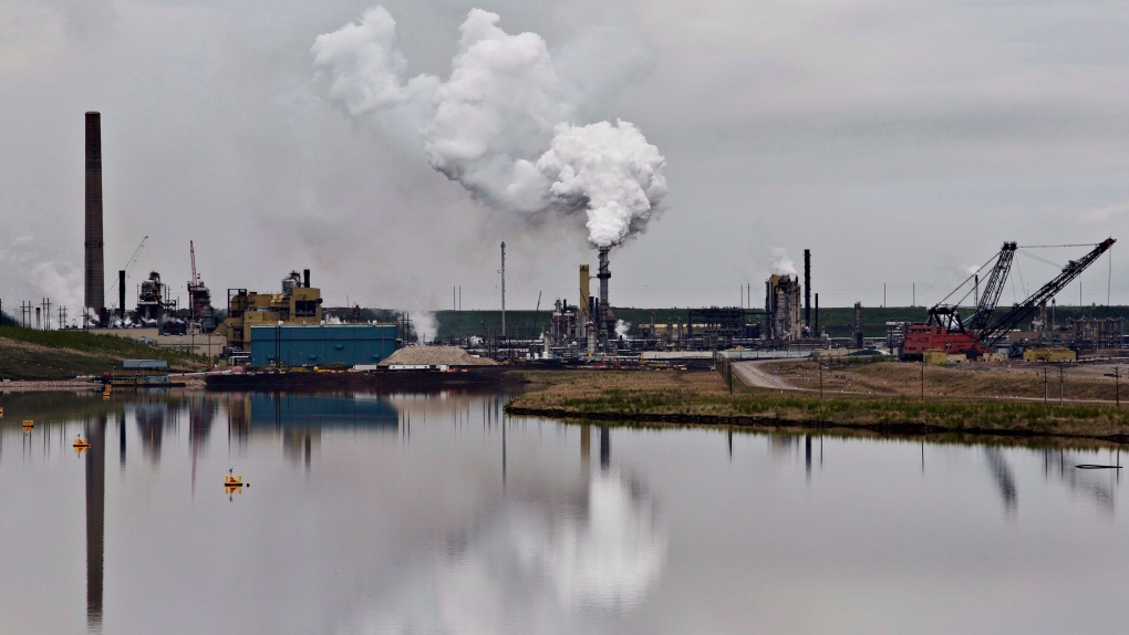 An oil sands extraction facility is reflected in a tailings pond near the city of Fort McMurray, Alta., on June 1, 2014. (THE CANADIAN PRESS/Jason Franson)