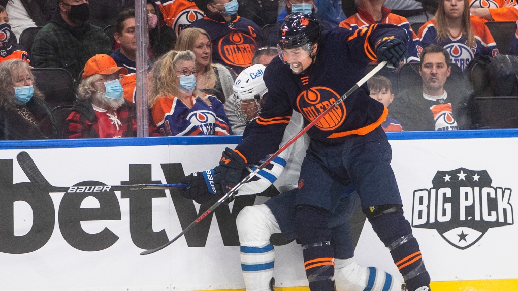 Winnipeg Jets' Dominic Toninato (21) is checked by Edmonton Oilers' Cody Ceci (5) during first period NHL action in Edmonton on Thursday, November 18, 2021.THE CANADIAN PRESS/Jason Franson 