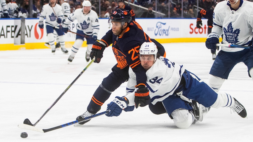 Toronto Maple Leafs' Auston Matthews (34) and Edmonton Oilers' Darnell Nurse (25) battle for the puck during first period NHL action in Edmonton on Tuesday, December 14, 2021.THE CANADIAN PRESS/Jason Franson 