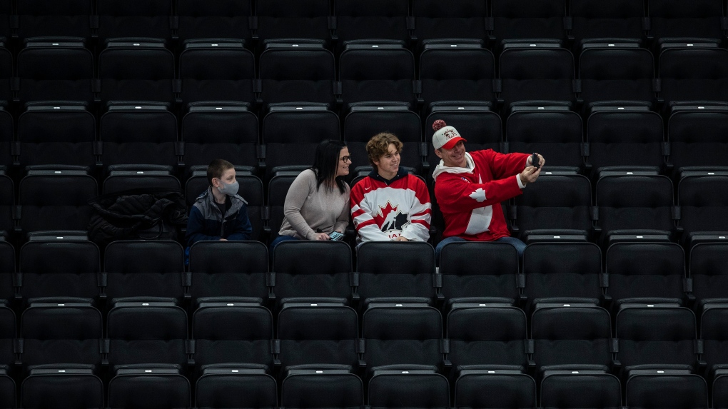 Fans take a selfie as they watch United States take on Finland during first period IIHF World Junior Hockey Championship exhibition action in Edmonton on Thursday, December 23, 2021. THE CANADIAN PRESS/Jason Franson 