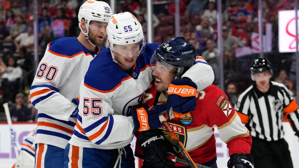 Edmonton Oilers left wing Dylan Holloway (55) wraps his arm around Florida Panthers left wing Ryan Lomberg (94) during the second period of an NHL hockey game, Saturday, Nov. 12, 2022, in Sunrise, Fla. (AP Photo/Lynne Sladky)