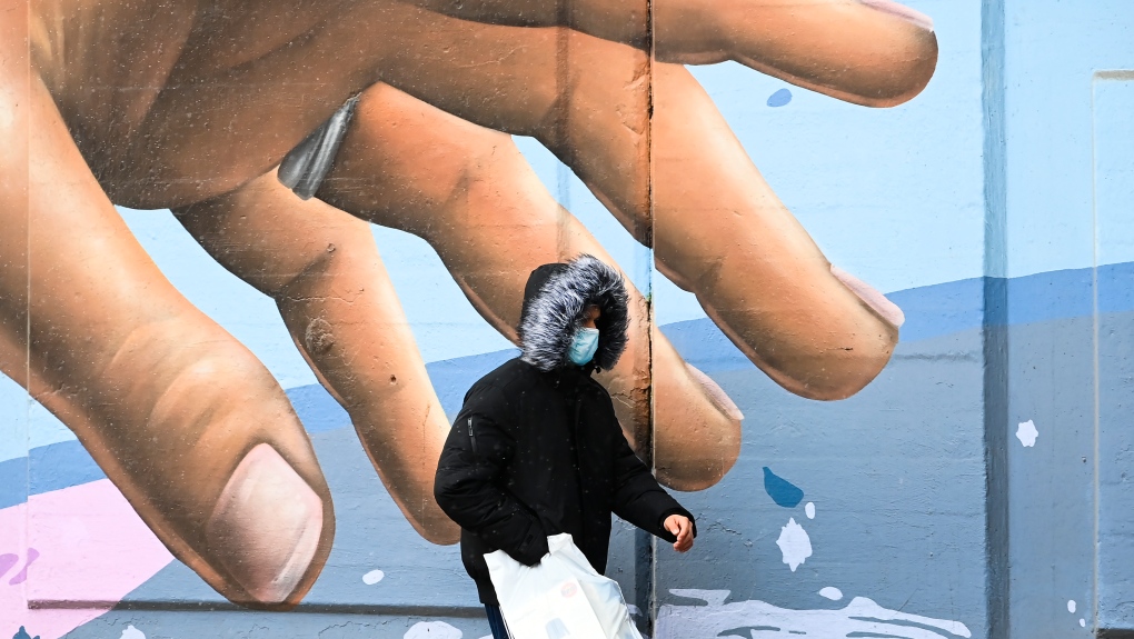 A man wearing a protective mask walks past a mural during the COVID-19 pandemic in Toronto on Tuesday, December 1, 2020. Toronto and Peel region continue to be in lockdown. THE CANADIAN PRESS/Nathan Denette