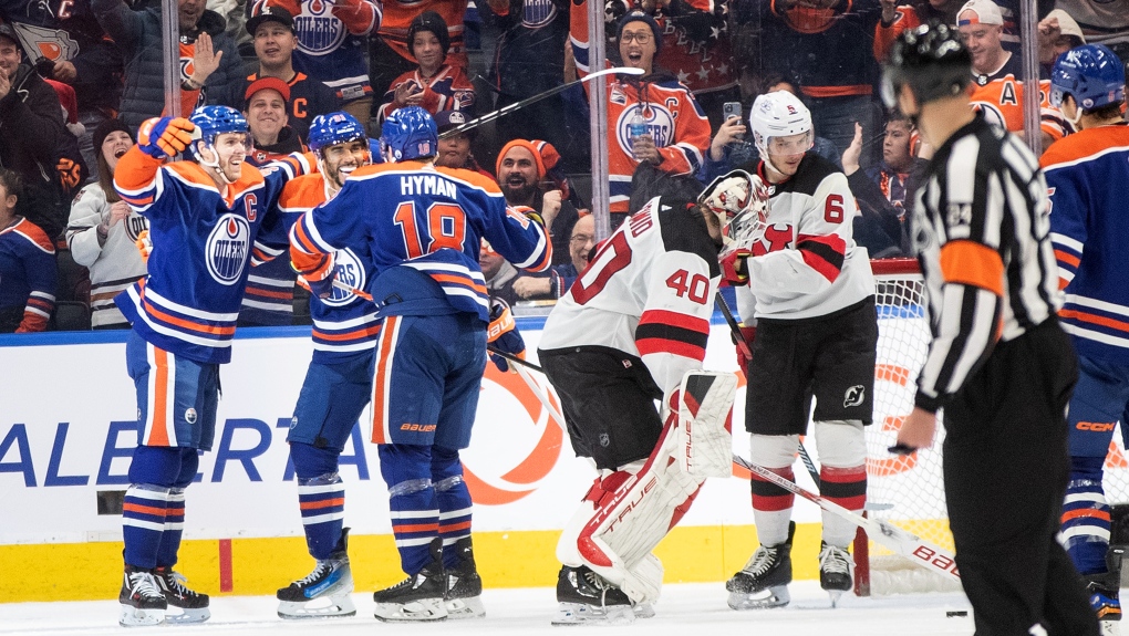 New Jersey Devils goalie Akira Schmid (40) and John Marino (6) react as Edmonton Oilers' Connor McDavid (97), Evander Kane (91) and Zach Hyman (18) celebrate a goal during third period NHL action in Edmonton on Sunday December 10, 2023.THE CANADIAN PRESS/Jason Franson