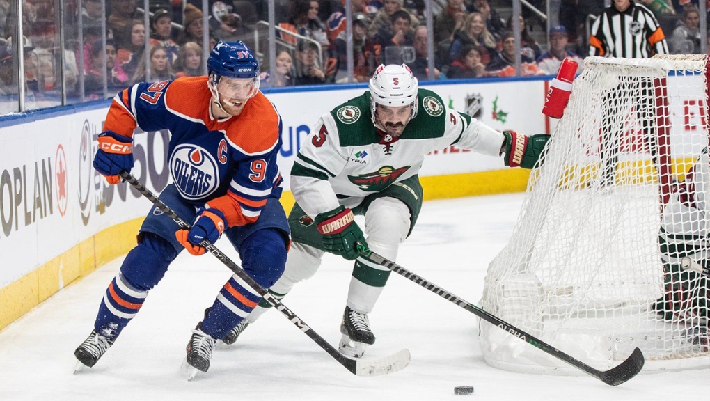 Minnesota Wild's Jacob Middleton (5) and Edmonton Oilers' Connor McDavid (97) battle for the puck during second period NHL action in Edmonton on Friday December 8, 2023. THE CANADIAN PRESS/Jason Franson