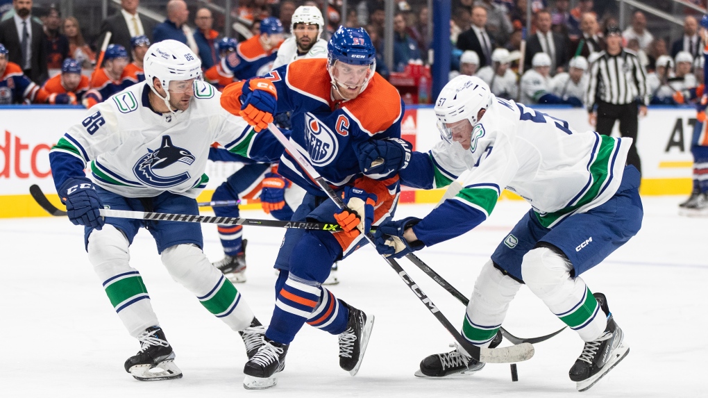 Vancouver Canucks defencemen Christian Wolanin, left, and Tyler Myers battle for the puck with Edmonton Oilers star Connor McDavid during NHL preseason action on Sept. 27, 2023, at Rogers Place. (Jason Franson/The Canadian Press)